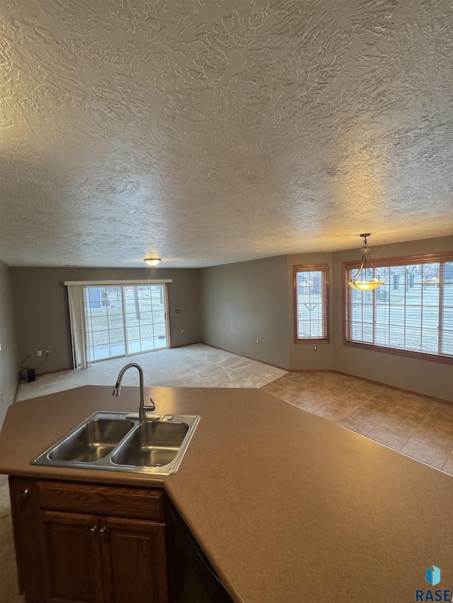 kitchen featuring decorative light fixtures, sink, a healthy amount of sunlight, and a textured ceiling