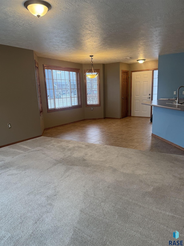 unfurnished living room with sink, light tile patterned floors, and a textured ceiling