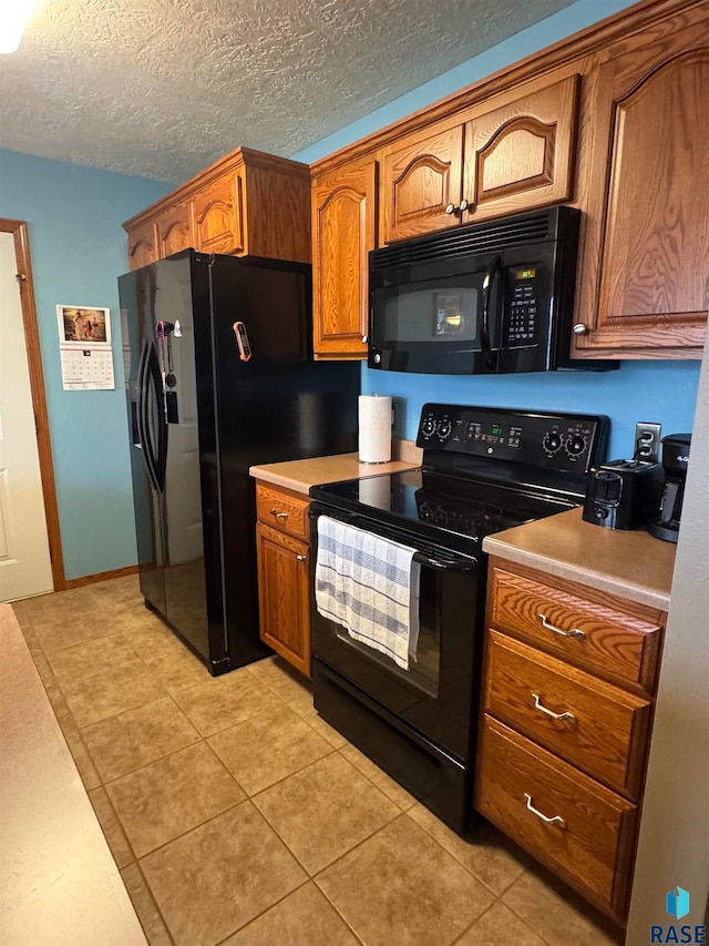 kitchen with black appliances, light tile patterned flooring, and a textured ceiling