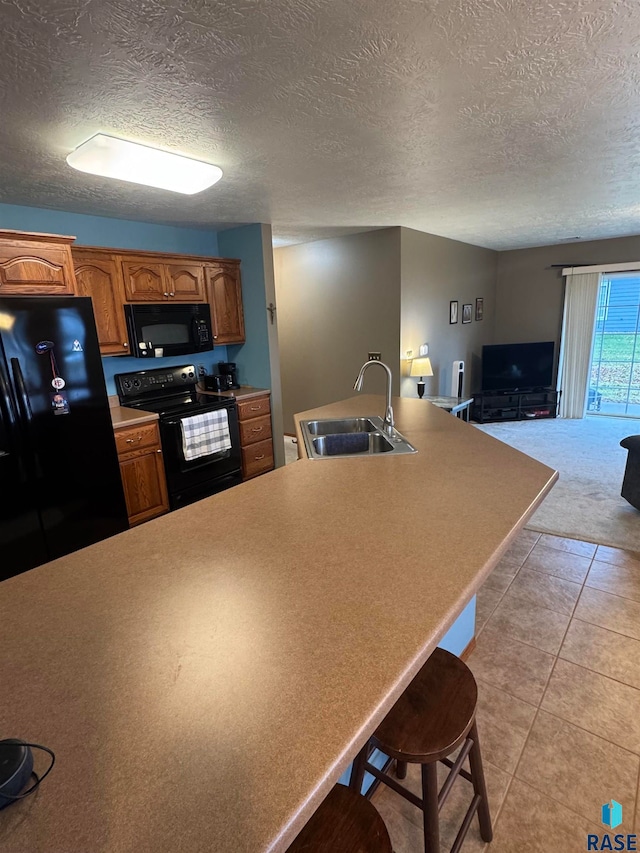 kitchen featuring a kitchen breakfast bar, a textured ceiling, sink, black appliances, and light tile patterned floors