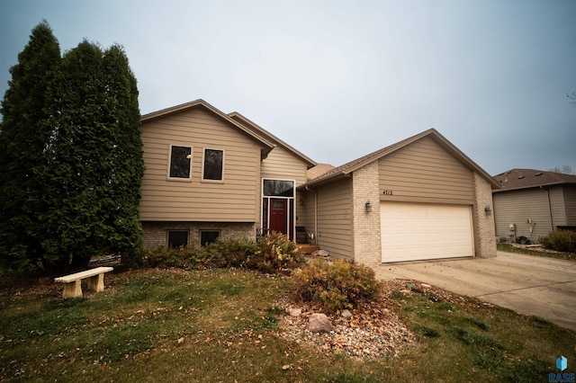 tri-level home featuring a garage, brick siding, and driveway