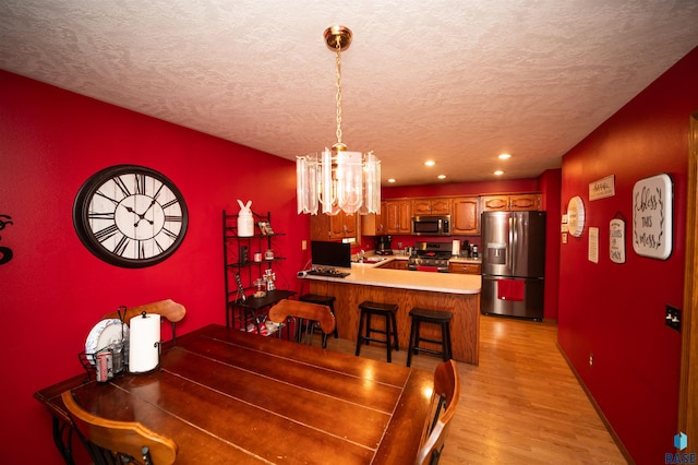 dining space with baseboards, recessed lighting, light wood-style flooring, a notable chandelier, and a textured ceiling