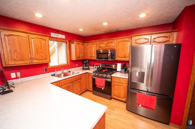 kitchen with a sink, brown cabinets, appliances with stainless steel finishes, and light countertops