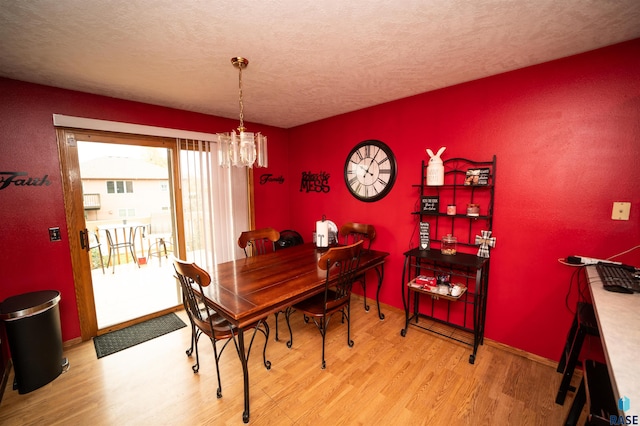 dining area with baseboards, a textured ceiling, an inviting chandelier, and wood finished floors