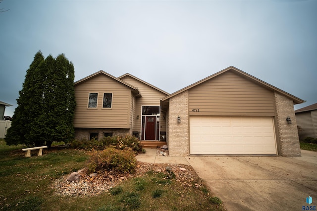 tri-level home featuring brick siding, an attached garage, and concrete driveway