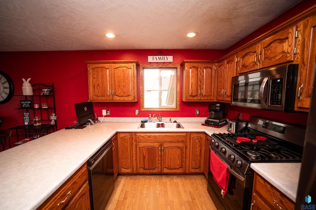 kitchen featuring a textured ceiling, light wood-type flooring, sink, and stainless steel appliances