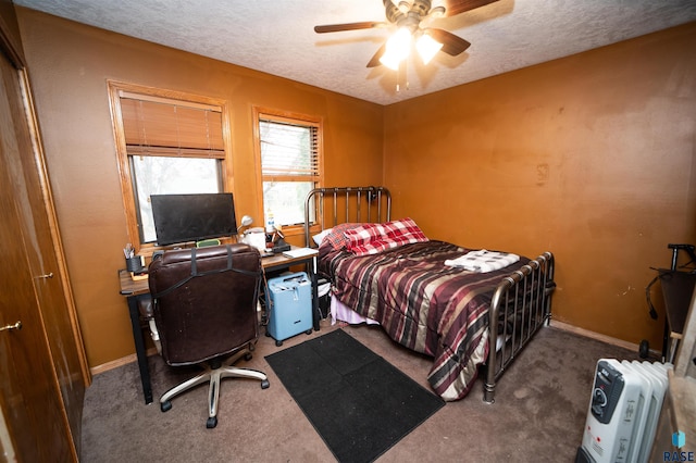 carpeted bedroom with a textured ceiling, baseboards, and a ceiling fan