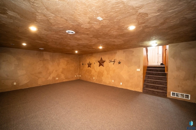 finished below grade area with visible vents, a textured ceiling, and stairway