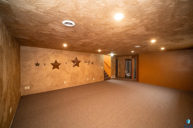 finished below grade area with stairway, carpet floors, a textured ceiling, and visible vents