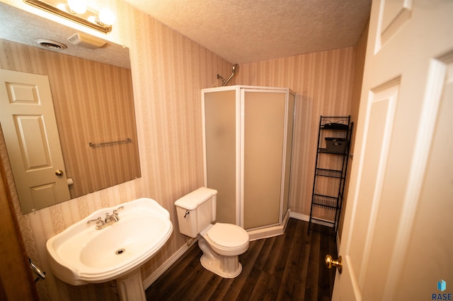 full bath featuring wallpapered walls, a shower stall, and a textured ceiling