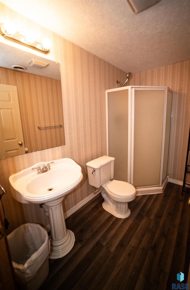 bathroom with wallpapered walls, a stall shower, and a textured ceiling