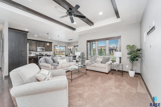 living room with wood-type flooring, a raised ceiling, and ceiling fan with notable chandelier