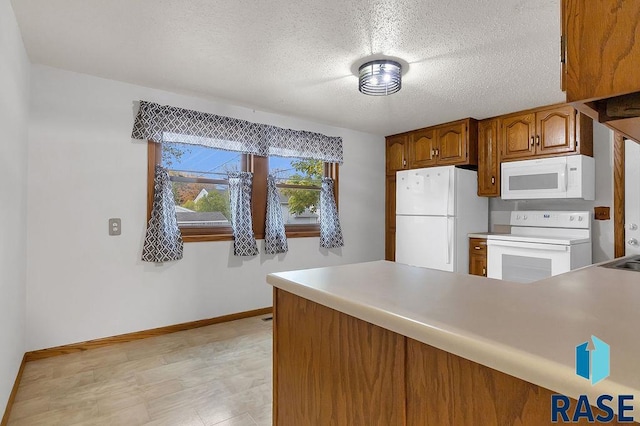 kitchen with kitchen peninsula, white appliances, and a textured ceiling