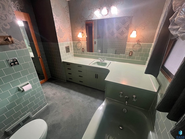 bathroom with tile walls, a bathing tub, vanity, and toilet