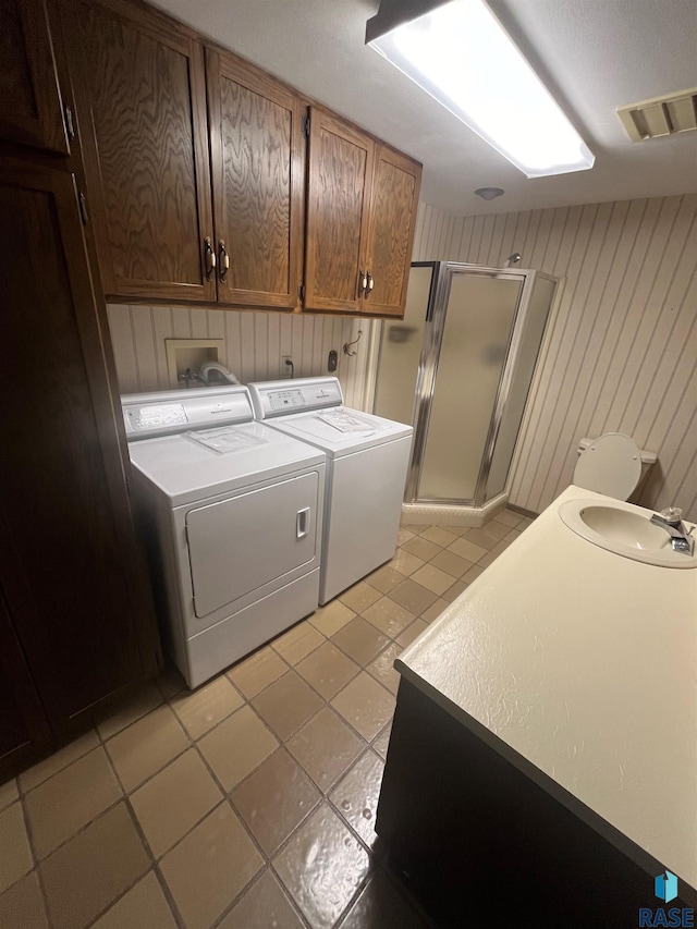 washroom featuring light tile patterned floors, cabinets, sink, and washer and dryer