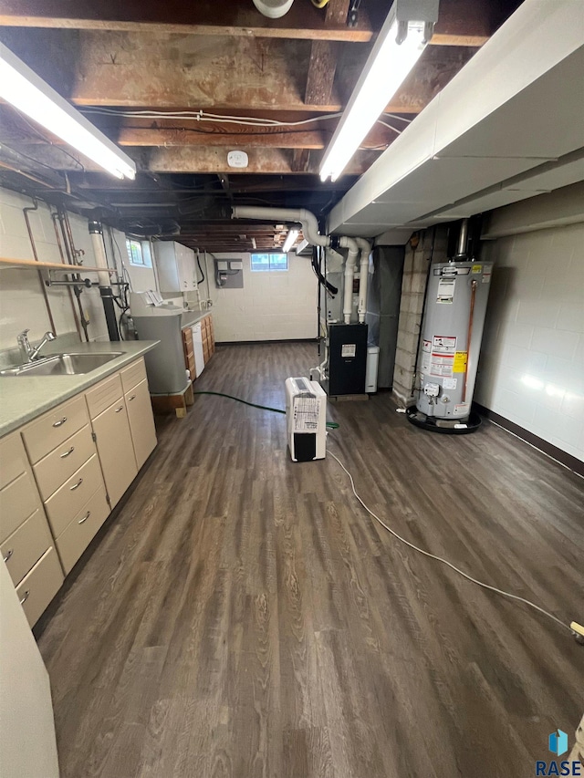 basement featuring heating unit, washer / dryer, dark hardwood / wood-style floors, water heater, and sink