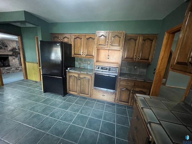 kitchen with black appliances, tile countertops, and tasteful backsplash