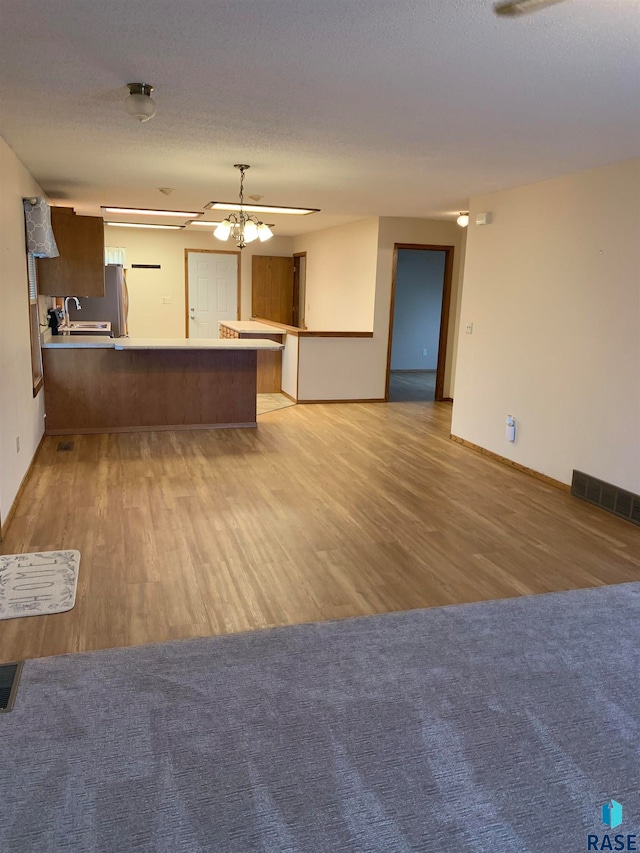 kitchen with kitchen peninsula, a textured ceiling, and light wood-type flooring