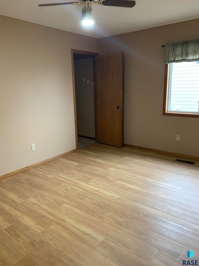 empty room with ceiling fan and light wood-type flooring