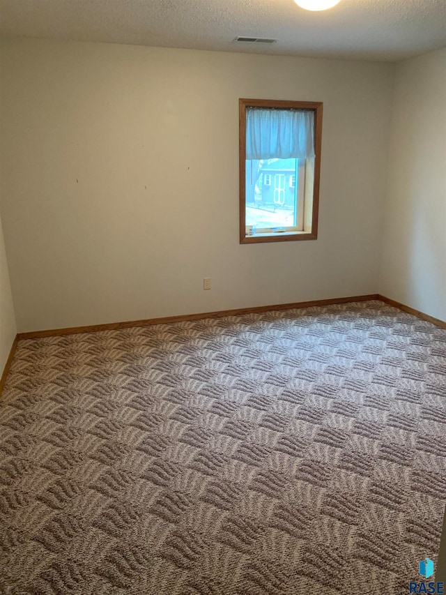 empty room featuring a textured ceiling and light carpet