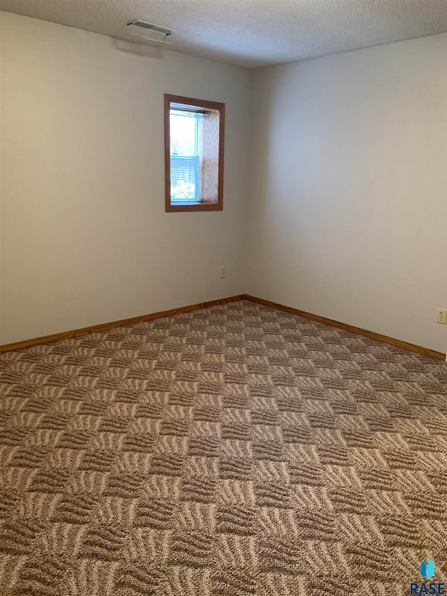 carpeted spare room featuring a textured ceiling