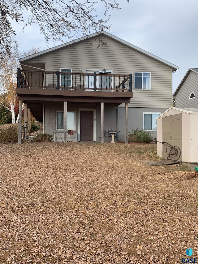 rear view of property featuring a wooden deck and a shed