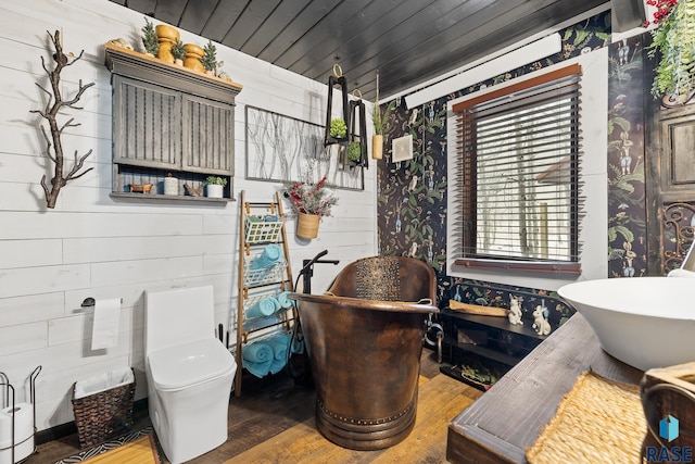 bathroom with a washtub, wood walls, hardwood / wood-style floors, toilet, and wood ceiling