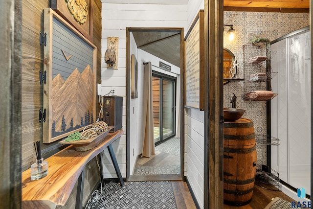 corridor featuring dark tile patterned flooring and wood walls