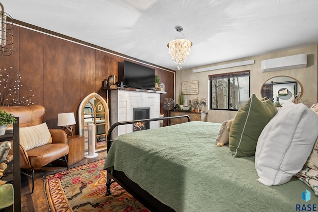 bedroom with a wall mounted air conditioner, wood walls, hardwood / wood-style flooring, a fireplace, and a chandelier