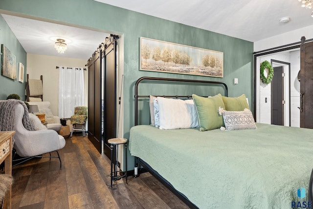 bedroom with a barn door and dark wood-type flooring