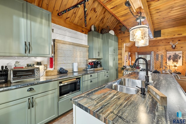 kitchen featuring hanging light fixtures, stainless steel microwave, and green cabinetry