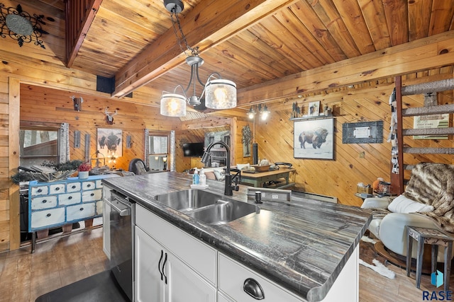 kitchen featuring wooden walls, dark wood-type flooring, a kitchen island with sink, and sink