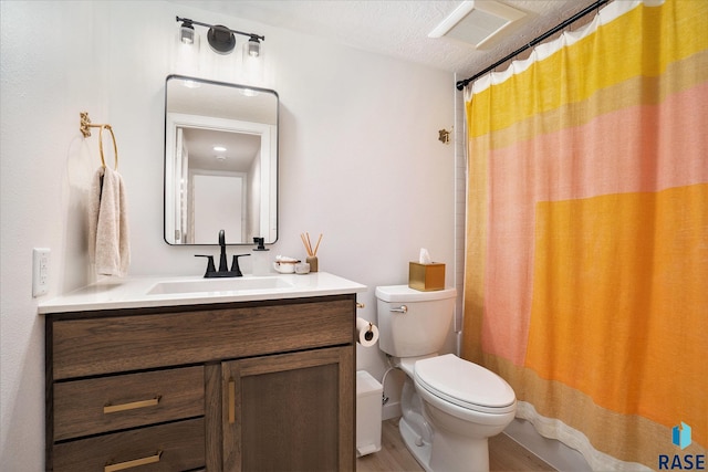 bathroom with hardwood / wood-style flooring, walk in shower, a textured ceiling, vanity, and toilet