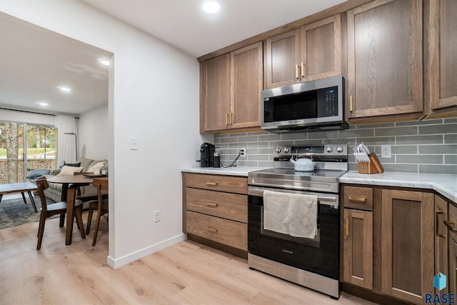 kitchen featuring tasteful backsplash, appliances with stainless steel finishes, and light hardwood / wood-style flooring