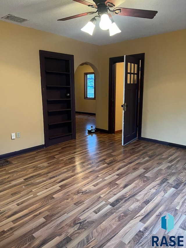 323 W Lincoln St, Luverne, MN 56156 - spare room with wood finished floors, a ceiling fan, arched walkways, and baseboards