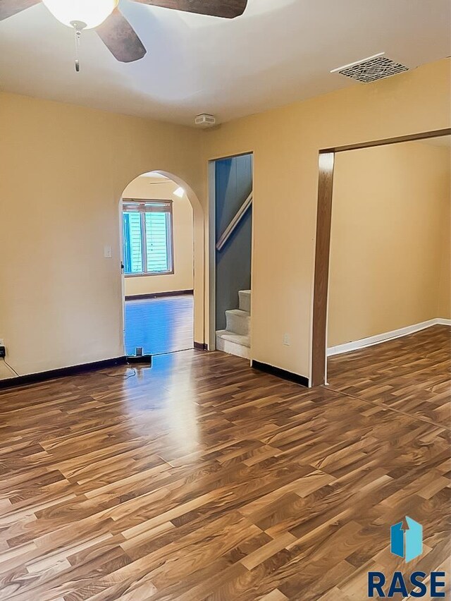 323 W Lincoln St, Luverne, MN 56156 - empty room with wood finished floors, ceiling fan, arched walkways, and stairs