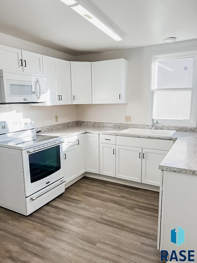 323 W Lincoln St, Luverne, MN 56156 - kitchen featuring white appliances, a sink, white cabinets, light countertops, and wood finished floors