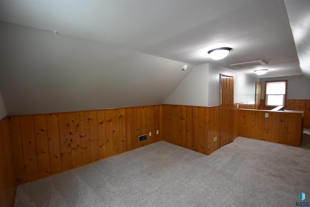 additional living space featuring wood walls, carpet, and lofted ceiling