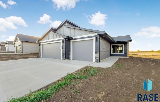 705 Sarah C St, Garretson, SD 57030 - view of front of property featuring board and batten siding, an attached garage, concrete driveway, and stone siding