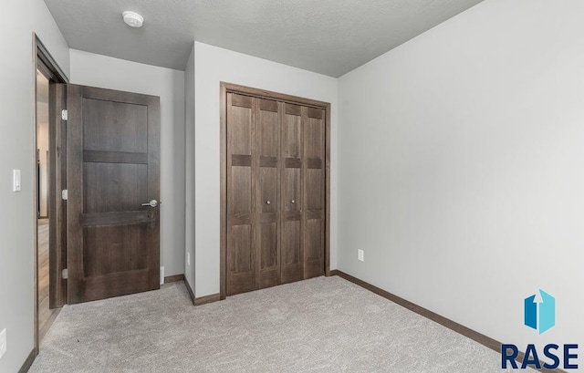 unfurnished bedroom with light carpet, a closet, and a textured ceiling