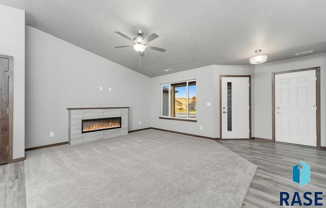 unfurnished living room featuring hardwood / wood-style floors, vaulted ceiling, ceiling fan, and a fireplace