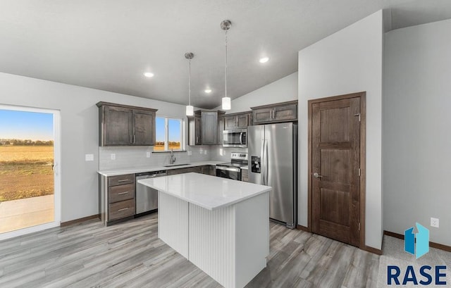 kitchen featuring sink, appliances with stainless steel finishes, lofted ceiling, a kitchen island, and pendant lighting