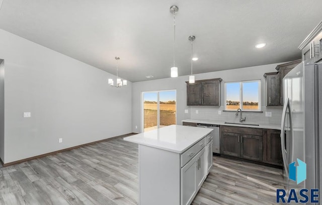 kitchen with a kitchen island, appliances with stainless steel finishes, a wealth of natural light, sink, and hanging light fixtures