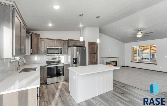 kitchen with stainless steel appliances, light hardwood / wood-style floors, vaulted ceiling, a kitchen island, and pendant lighting