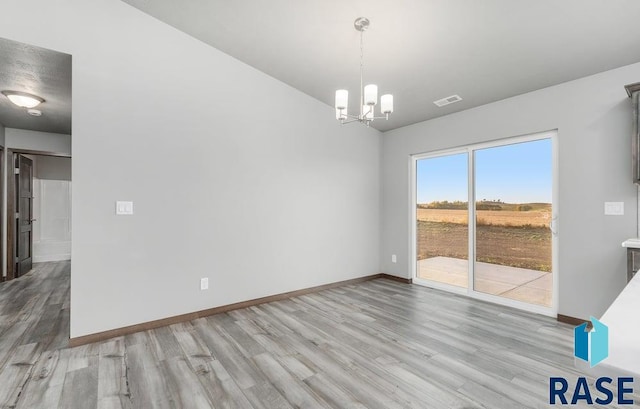 unfurnished dining area with a notable chandelier and light hardwood / wood-style flooring