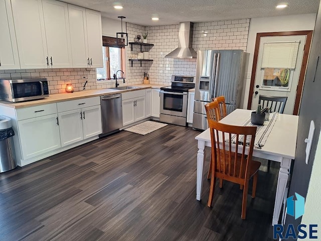 kitchen with stainless steel appliances, dark wood-type flooring, wall chimney exhaust hood, sink, and white cabinetry