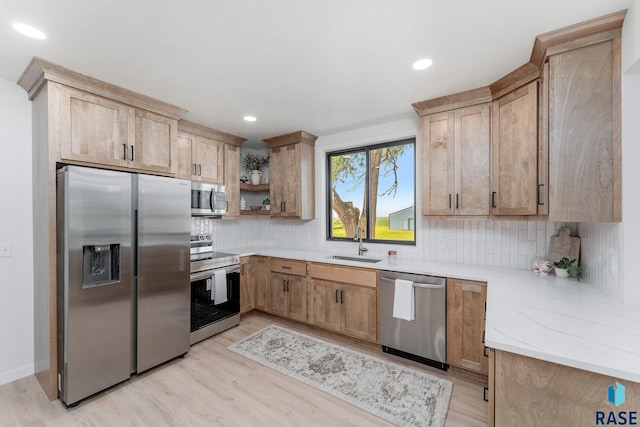 kitchen featuring stainless steel appliances, light wood-type flooring, backsplash, light stone countertops, and sink