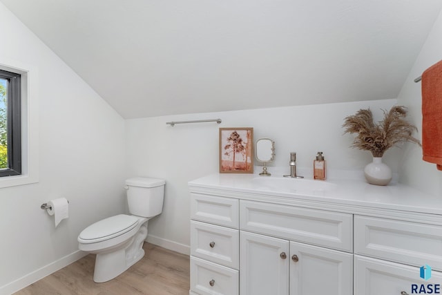 bathroom featuring hardwood / wood-style floors, lofted ceiling, toilet, and vanity