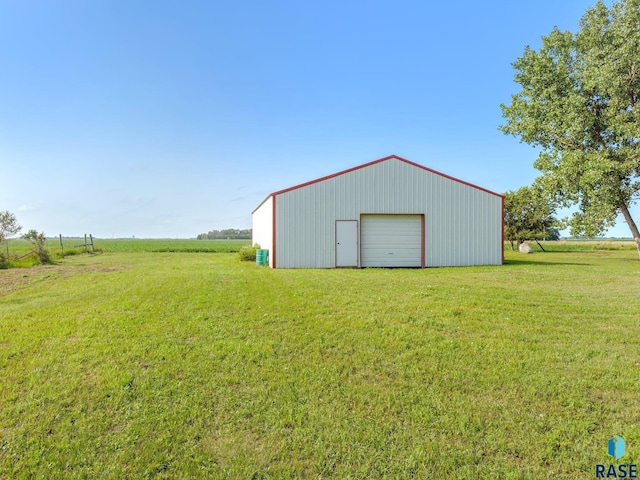 view of outbuilding featuring a lawn, a garage, and a rural view