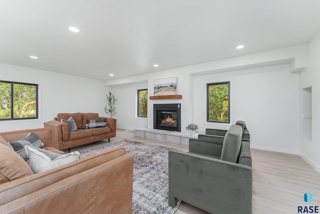 living room with a wealth of natural light, a tile fireplace, and light hardwood / wood-style flooring